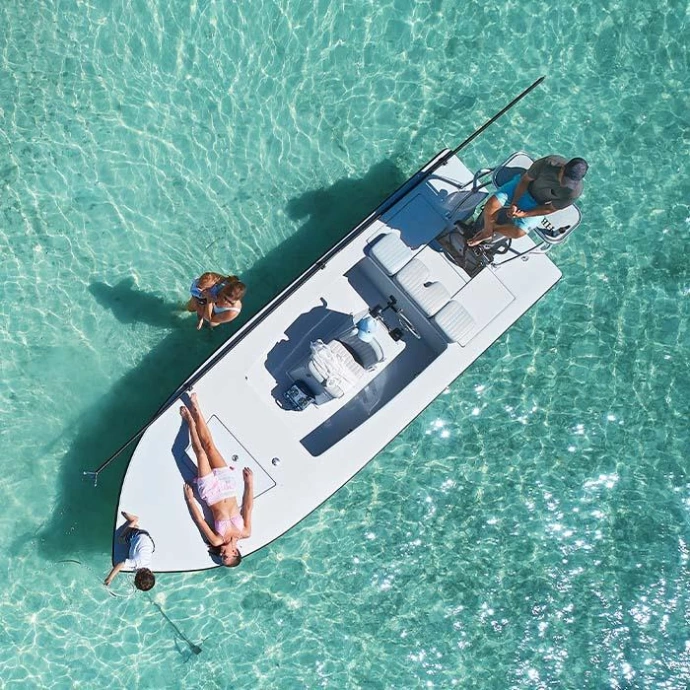 Aerial view of people enjoying a small boat in clear turquoise tropical water.